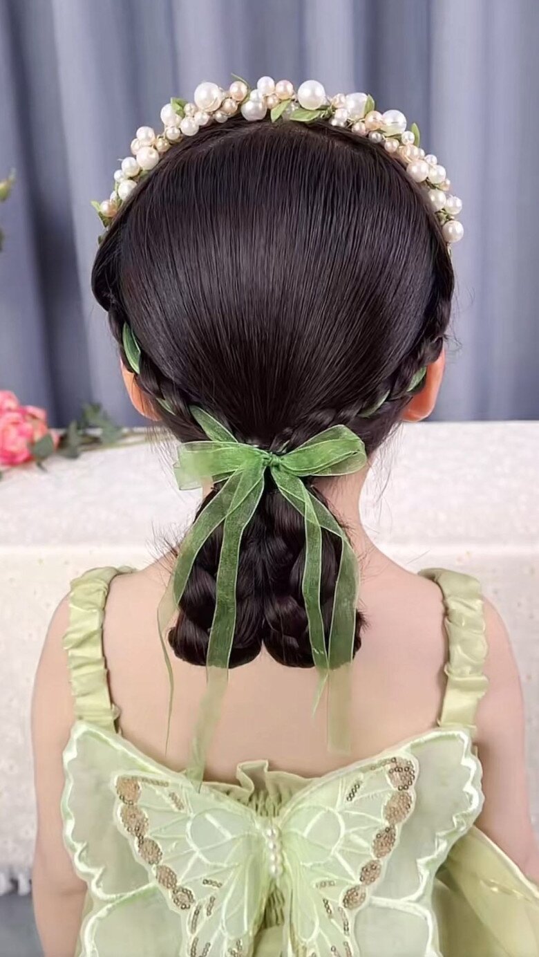 Kiểu tóc tết vòng quanh đầu, phần đuôi cũng tết và buộc gọn lại. Một chiếc nơ xinh sẽ giúp con trông giống công chúa hơn.