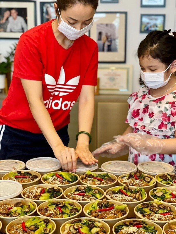 Cô bé cùng mẹ vào bếp nấu những suất ăn gửi nơi chống dịch.