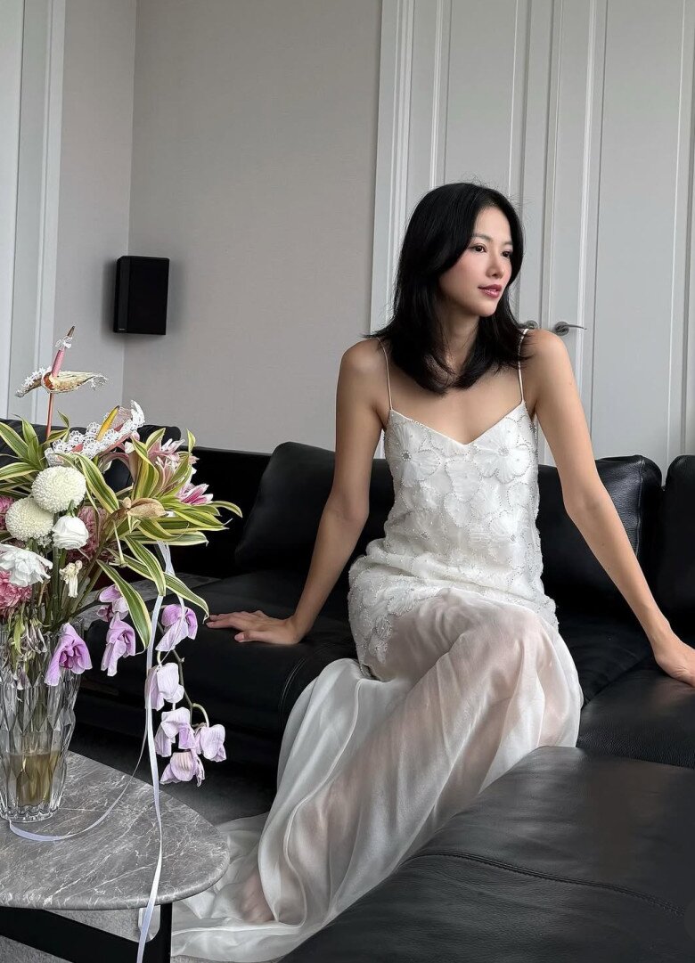 Người đẹp diện chiếc slip dress trắng – kiểu váy tưởng chừng đơn giản nhưng khi khoác lên lại mang đến nét sang nhẹ như sương. Màu trắng tinh khôi tôn làn da và giúp cô hòa mình vào không gian café mộc mạc. Mái tóc buông nhẹ, đôi giày bệt nhỏ xinh – cả tổng thể như được “giảm âm” để tôn lên sự nữ tính và tự tin của người phụ nữ hiện đại.