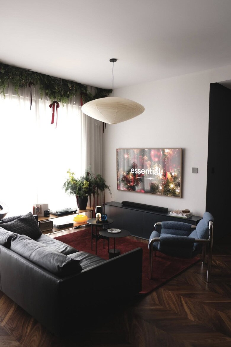 Dải lá thông và lá xanh được thả rủ nhẹ nhàng dọc trần cửa kính, điểm xuyến ruy băng đỏ trầm.