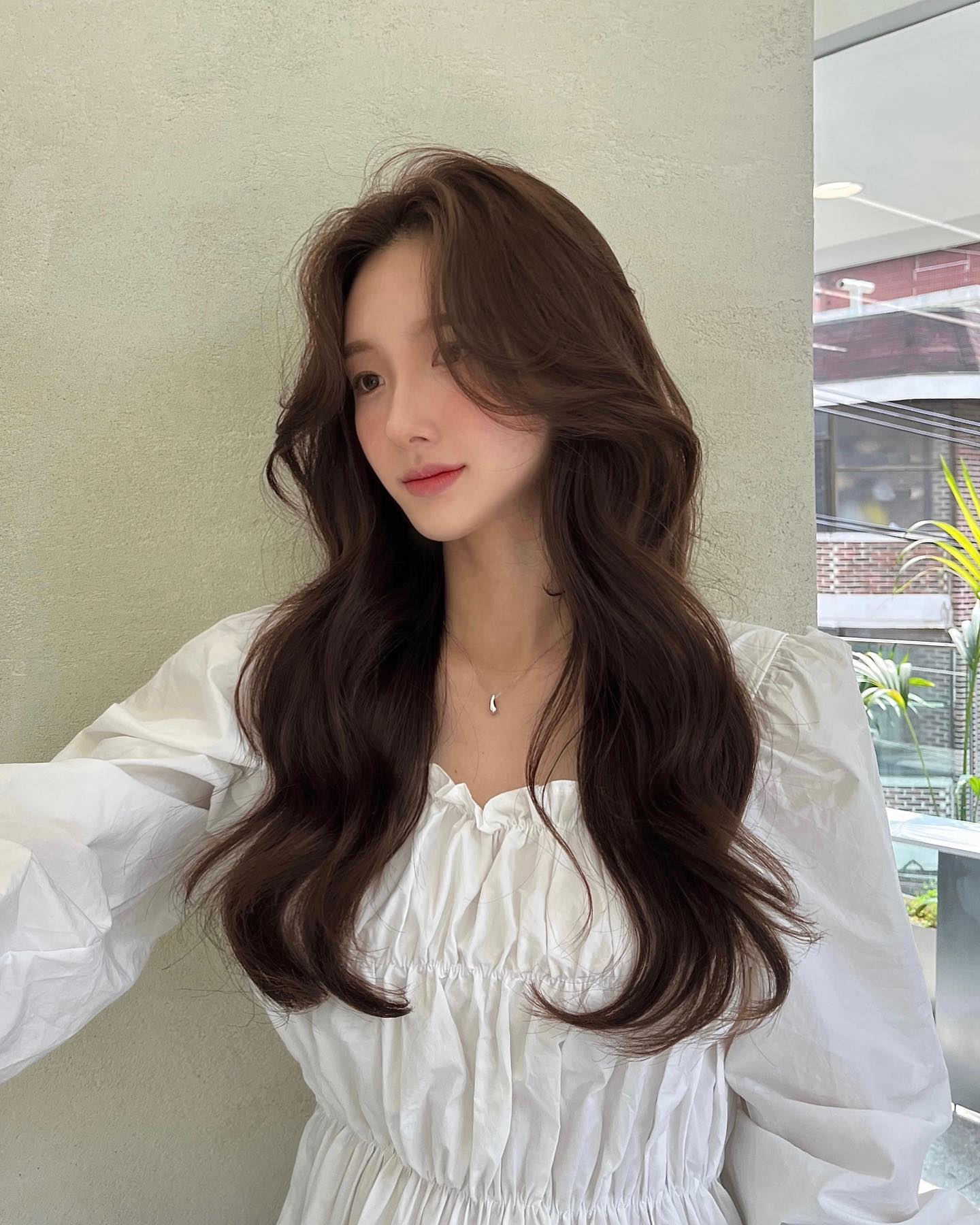 Tóc dài uốn sóng nhẹ giúp mái tóc mỏng trông dày gấp đôi. Các lọn sóng mềm mại ôm lấy gương mặt, tạo hiệu ứng nhỏ gọn và thanh thoát. Diện kiểu này, nàng nào cũng hóa nữ chính dịu dàng.