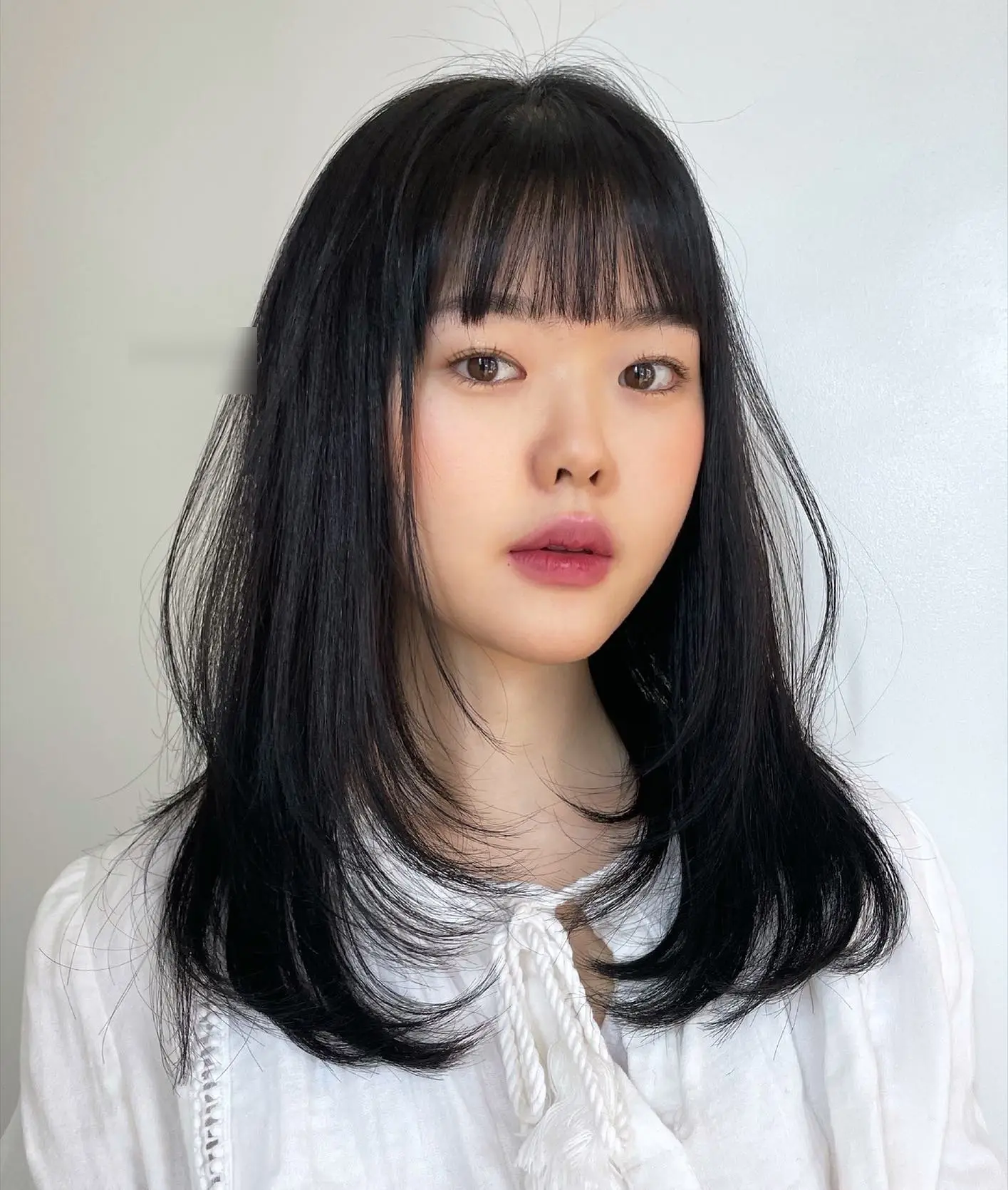 Đuôi tóc cụp ôm sát hàm giúp giấu mặt tròn cực khéo. Kiểu tóc đơn giản, chỉn chu này tạo cảm giác gương mặt nhỏ, gọn và rất thanh lịch.