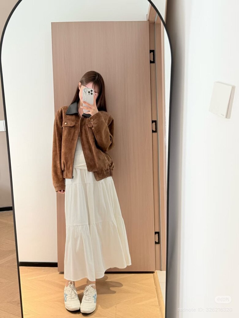 Chân váy midi xếp ly kết hợp thiết kế khoác ngoài dáng ngắn mang đến vẻ nữ tính, giúp tổng thể trang phục thêm mềm mại.