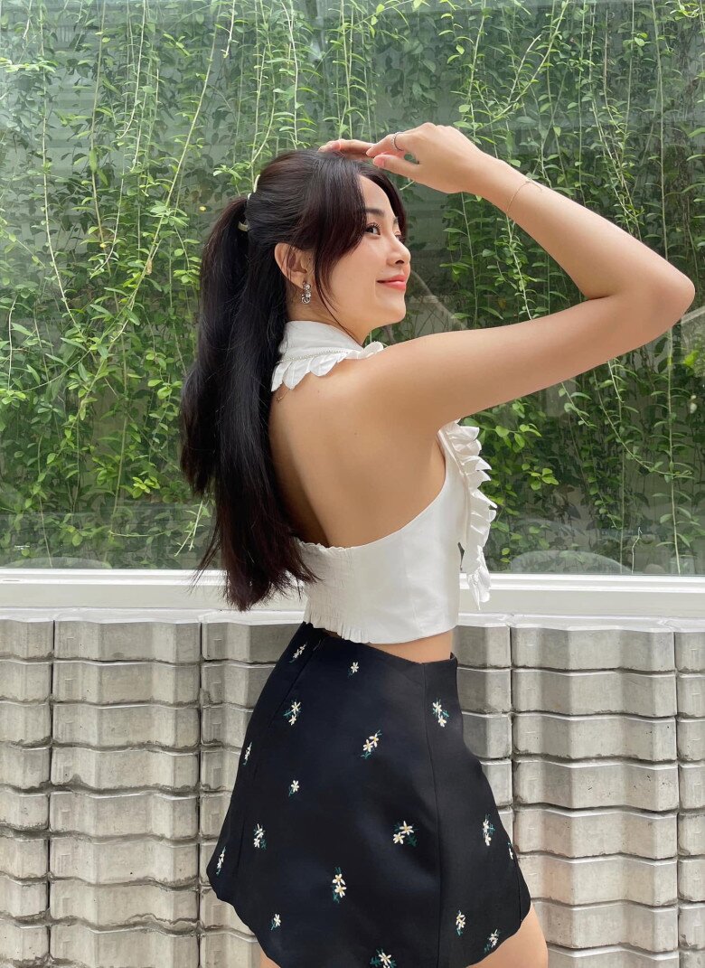 Lê Tam Triều Dâng kết hợp áo yếm croptop trắng viền bèo cùng chân váy ngắn đen họa tiết hoa nhí, tạo nét nữ tính mà không cầu kỳ. Phần lưng trần trở thành điểm nhấn, tôn bờ vai thanh mảnh và đường nét cân đối.